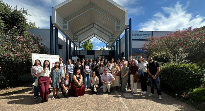 Un grupo de personas posando frente a un edificio con un cielo azul